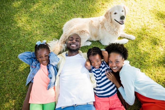 Happy family lying in green grass with dog