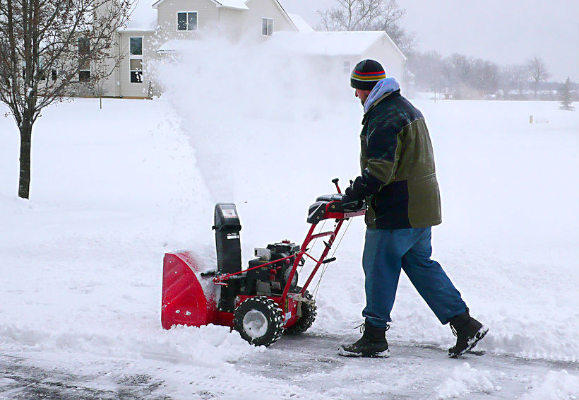 Man pushing a red snow blower